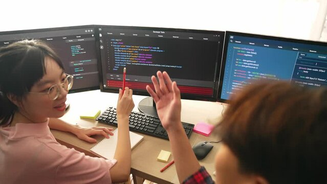 Slow motion back end software developer engineer for computer programming working together on debugging writing computing code, solving complex algorithms display on monitor in office. Burgeoning