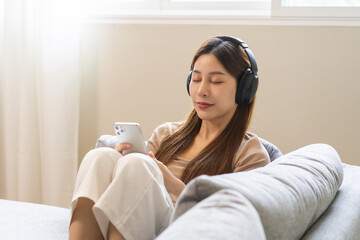 Relaxing asian young woman using smart phone listening to music, enjoy song or watching videos,...
