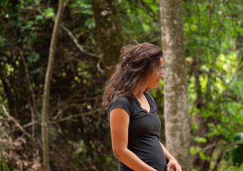 Naklejka na ściany i meble Femme vue de profil avec un t-shirt noir et des cheveux bruns décoiffés attendant dans la forêt