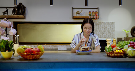 Asian Indian Hindu happy teen girl sitting modern kitchen eating hold spoon sweet tasty pastry cake food snacks tasting bite indoor house cute teenager female enjoy fun joy holiday home 