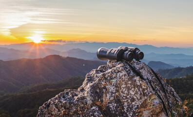 binoculars on top of rock mountain at beautiful sunset background. - obrazy, fototapety, plakaty