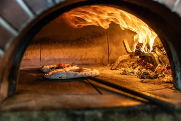 Foto op Plexiglas anti-reflex Traditional oven for baking pizza with burning wood and shovel. The cook rotates the pizza in the oven to ensure even baking © weyo