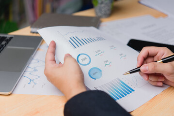 Close-up of a professional hand reviewing business document data performance analytics and printing...
