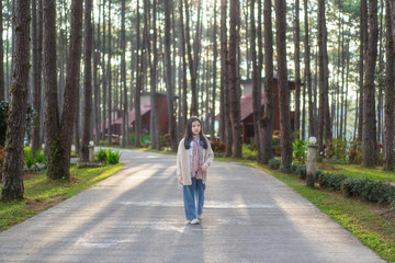 Asian child travel or kid girl happy smile walking in pine forest or nature trees garden with soft sunlight on morning and wearing scarf sweater or coat on holiday at Doi Bo Luang Forest Park Resort