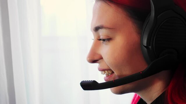 Young adult Caucasian woman works as an online operator in a call center. Her cheerful and polite demeanor as she assists clients through a headset utilizing headphones and a microphone. Remote job