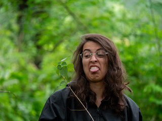 Portrait d'une femme brune qui tire la langue avec un air grincheux regardant une brindille, en...