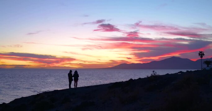 silhouette of a couple standing on a rock during sunset