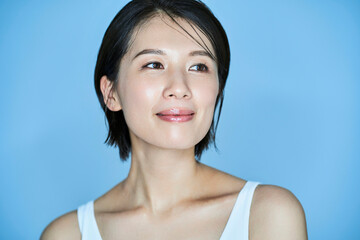 無地の背景の前に立つ女性・美容イメージ