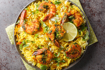 Asian saffron pilaf with shrimp and lots of herbs such as dill, green onions, cilantro close-up on a plate on the table. Horizontal top view from above