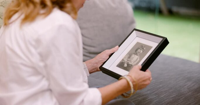 Photo, frame and hands of person with memory, nostalgia, and thinking of past family in home. Photography, closeup and woman remember girl from history with grief, mourning and depression from death