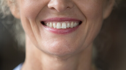 Close up shot lower face view of happy mature woman pose for camera, having wide toothy smile...