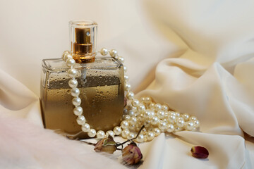 Blank perfume bottle with gold and marble cup in front of a brunch of cherry blossom. Photography in beige tones