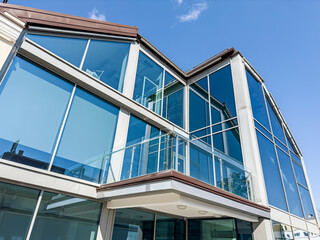 facade of small office building with reflections of blue sky on sunny day