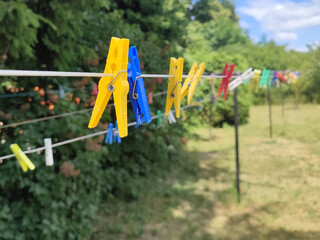 Fototapeta premium Colored laundry clothespins plastic. Hanging on clothesline, outdoors