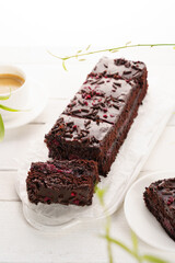 Chocolate cake with cherry, cut into portions, white wooden background, vertical format