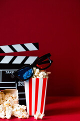 A banner for the film industry. A romantic movie date. A movie camera, 3D glasses, popcorn in striped cups on a red background. The premiere of the film.