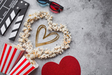 A banner for the film industry. A romantic movie date. A movie camera, 3D glasses, popcorn and a popcorn heart on a stylish concrete-gray background. The film will premiere on Valentine's Day.