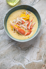 Bowl of crab and corn soup on a light-grey granite background, vertical shot, copy space, high angle view