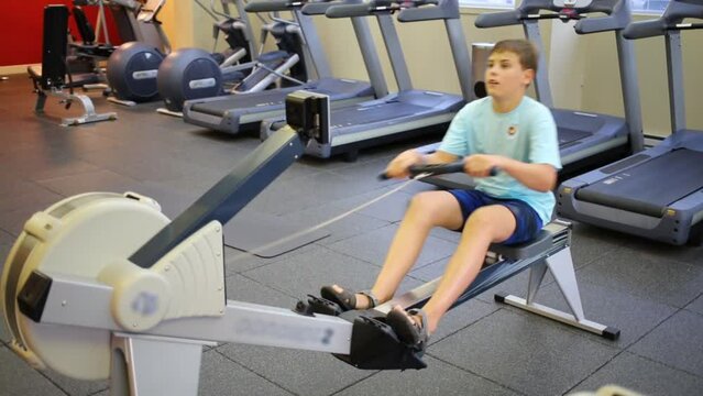 Boy teen training simulator in modern fitness center