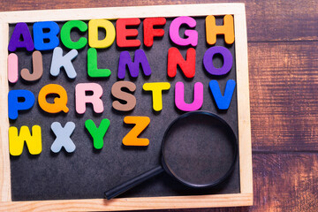 English letters made from square wooden tiles There are English letters scattered on a black...