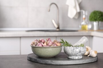 Fresh raw garlic and rosemary on grey table, space for text