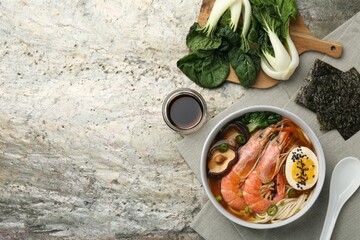 Delicious ramen with shrimps and egg in bowl served on grey textured table, flat lay with space for...