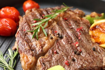 Delicious grilled beef steak, tomatoes and rosemary in frying pan, closeup