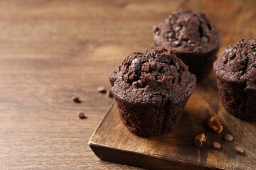 Delicious chocolate muffins on wooden table, closeup. Space for text - obrazy, fototapety, plakaty