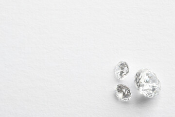 Obraz na płótnie Canvas Beautiful shiny diamonds on white background, flat lay. Space for text