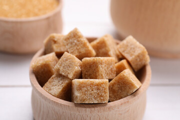 Brown sugar cubes in bowl on table, closeup