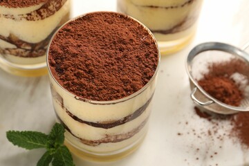 Delicious tiramisu in glasses and mint on table, above view
