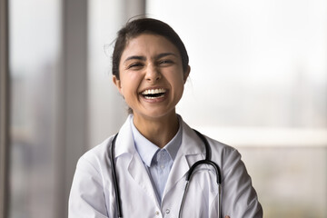 Cheerful Indian doctor woman in uniform with stethoscope looking at camera, laughing out loud, posing for head shot portrait, having fun, enjoying medical profession, successful career in medicine - obrazy, fototapety, plakaty
