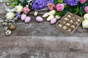 Blumenarrangement mit Oster und Wachteleiern auf schäbigem Holz mit Platz für Text.