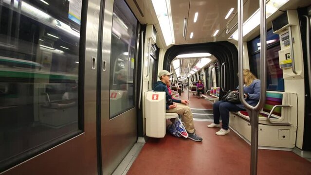 Children sit on seats of fast moving subway train car.
