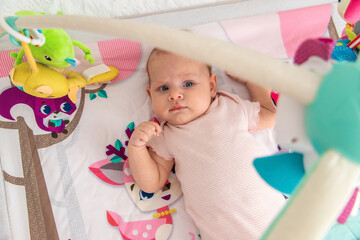 a baby plays with hanging toys on a play mat. a child, a baby plays at home