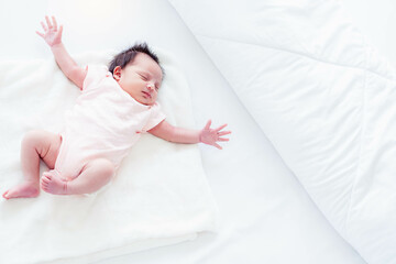 Portrait adorable newborn baby happy dreaming stretching and stretch lazily on bed at home topview...