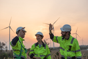 Team of engineers working on site in wind turbine farm, Wind turbines generate clean energy source,...