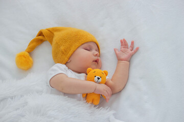 a baby in a white bodysuit is sleeping on a white background, hugging a bear. child.