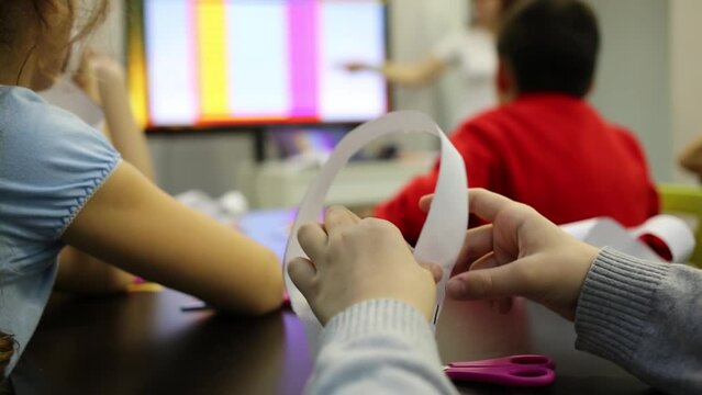Children sits at the table with scissors and listen to teacher