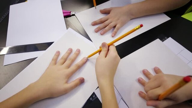 Children leads round by pencil their hands in classroom