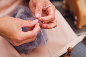 The woman's hobby is spinning silk thread using a retro spinning wheel.