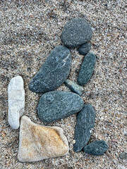 stones on the sand. stones on a beach placed in the shape of a man sitting on the toilet. detail.