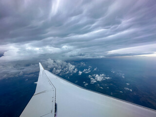 wing of an airplane in flight with storm cloud background.
