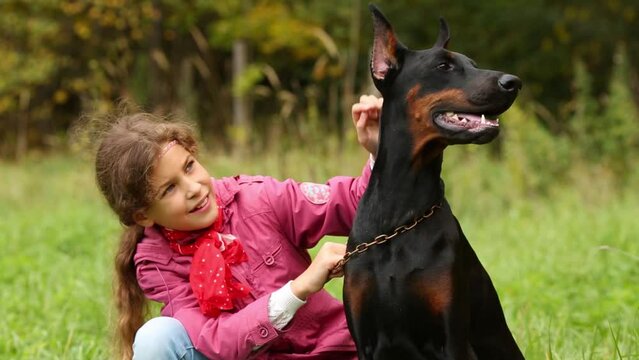 Pretty girl strokes her black dog in autumn forest
