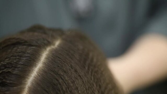 Closeup visagiste hands combs hair of female model.