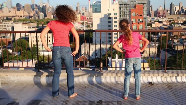 Mother and daughter do morning exercises on roof in New York