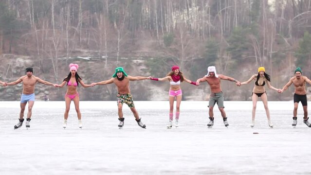 Eight young people skate as chain on natural ice rink at winter