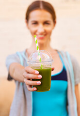 Fototapeta premium Woman drinking vegetable smoothie after fitness running workout on summer day