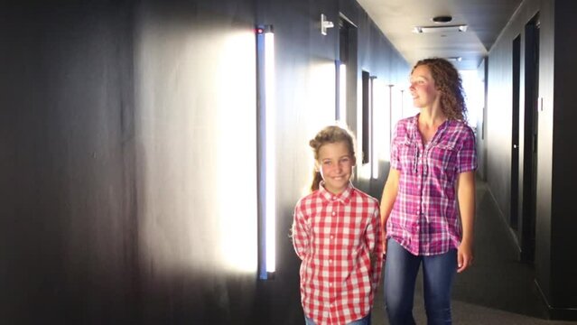 Woman and girl go in hallway with illuminated walls