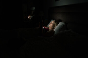 woman in bed before going to sleep with phone in hand